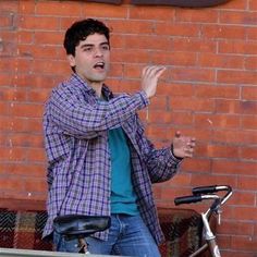 a man standing in front of a brick wall with his hands out to the side