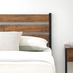 a bed with white pillows and wooden headboard next to a night stand on the floor