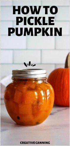 an orange jar filled with pickle sitting on top of a counter next to two pumpkins