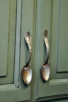 two spoons are on the handle of a green cabinet