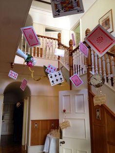 some cards are hanging from the ceiling in a house with stairs and railings on both sides