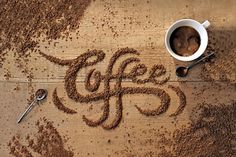 the word coffee written in sand next to a cup of coffee