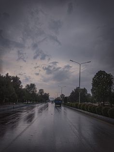 the street is wet and dark with some clouds in the sky overcast skies above