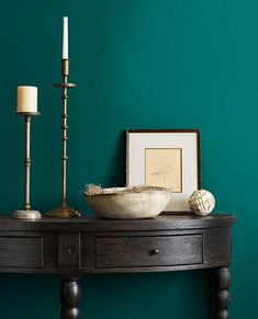 a wooden table topped with a bowl and two candles