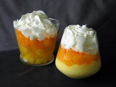 two desserts with orange and white frosting in small glass dishes on a black surface