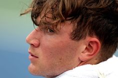 a close up of a man holding a tennis racquet in his hand and looking off to the side