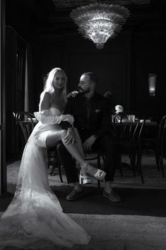 a man and woman sitting at a table in black and white