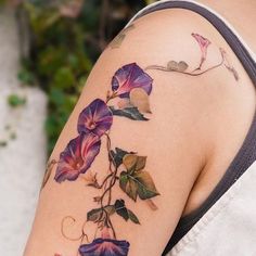 a woman's arm with purple flowers and vines on the left side of her body