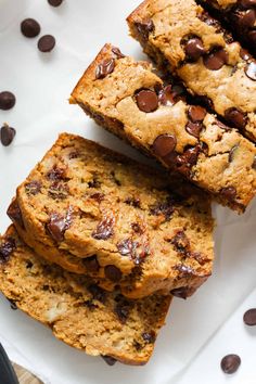 three chocolate chip banana breads on a white plate with chocolate chips scattered around them