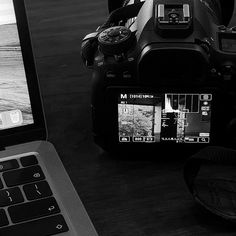 a laptop computer sitting on top of a wooden table next to a camera and another electronic device