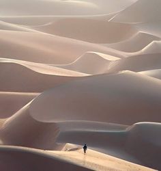 a lone person is walking through the sand dunes