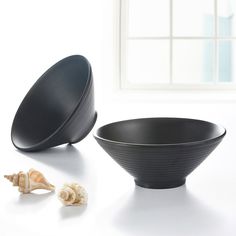 two black bowls sitting on top of a white table