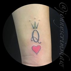 a small tattoo with the letter q and a crown on it's side leg