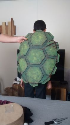 a man is holding up a turtle costume