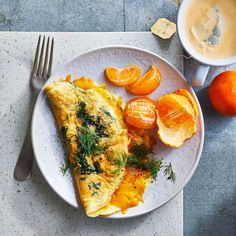 an omelet on a plate with oranges, and a cup of coffee