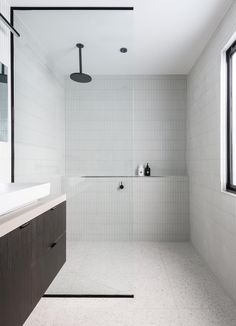 a white tiled bathroom with black accents