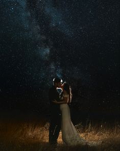 a bride and groom kissing under the night sky