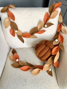 a white chair with an orange and brown leaf decoration on it's armrest