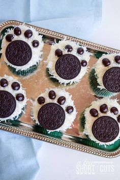 four cupcakes decorated with oreo cookies and white frosting on a tray