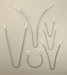 four surgical instruments are shown on a white surface with wires attached to the top of them