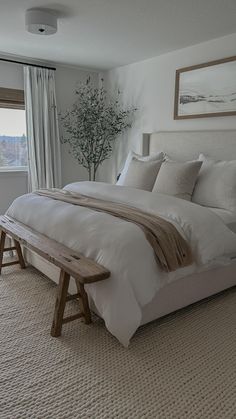 a large bed sitting in a bedroom next to a window with drapes on the windowsill