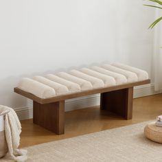 a wooden bench sitting on top of a hard wood floor next to a potted plant