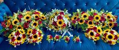 sunflowers and other flowers are arranged on a blue couch