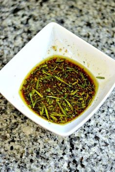 a square white bowl filled with green herbs