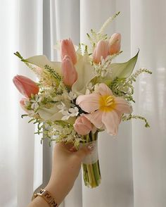 a person holding a bouquet of flowers in their hand with white and pink colors on it