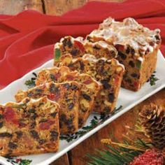 several pieces of fruitcake on a plate with pine cones and red napkins in the background