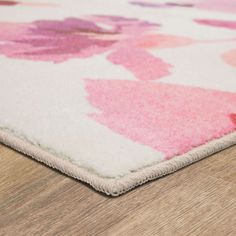 a pink and white area rug with flowers on the bottom, sitting on a wooden floor