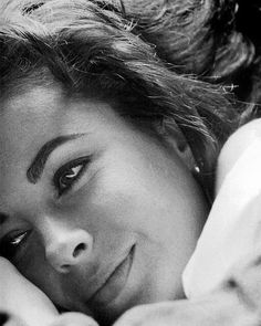 a black and white photo of a woman laying in bed with her hand on her face