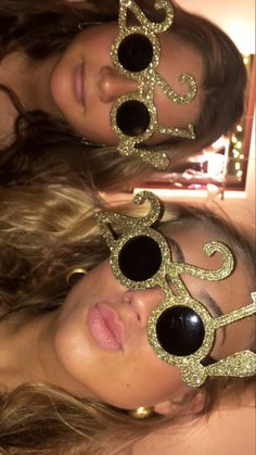 two women wearing sunglasses with the word love spelled in gold glitter on their faces and arms