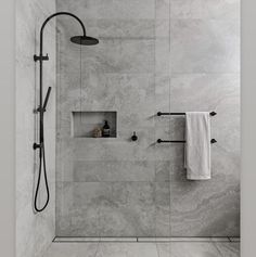 a bathroom with a shower head, towel rack and toilet paper dispenser