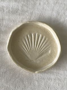 a small white bowl sitting on top of a tablecloth covered floor next to a wall