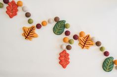 felt autumn leaves and acorns are arranged on a white surface with small balls