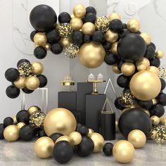 black and gold balloons are in the shape of an arch, surrounded by other decorations