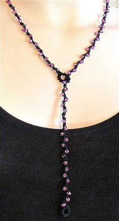 a woman wearing a necklace with purple beads and a black beaded tassel hanging from it's neck