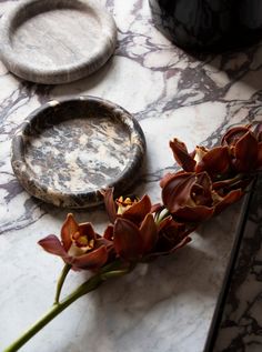 some flowers are sitting on a marble table with a plate and tray in the background