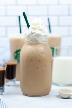 there are three drinks on the table and one is in a mason jar with whipped cream