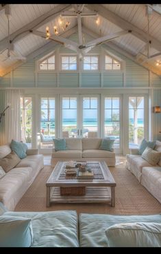 a living room filled with white furniture and windows covered in blue shuttered glass doors