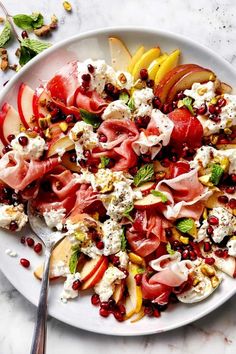 a white plate topped with fruit and feta cheese covered in pomegranate