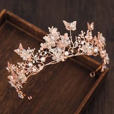 a tiara with flowers and butterflies on top of a wooden tray next to a pair of scissors