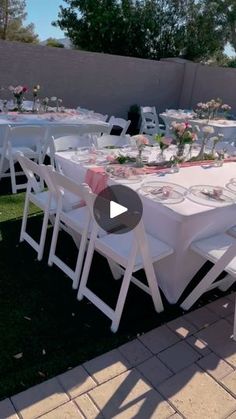 a table set up with white chairs and pink linens for an outdoor wedding reception