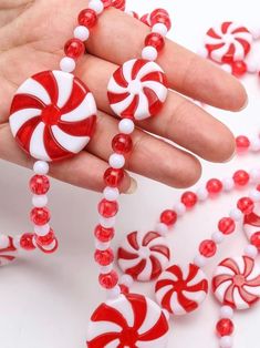 a hand is holding some candy canes on a string with beaded beads around it