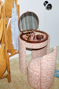 a small round table with a mirror on it and two stools next to it