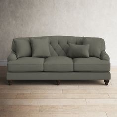 a gray couch sitting on top of a hard wood floor next to a white wall