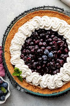 a blueberry pie with whipped cream and fresh berries on the top is ready to be eaten