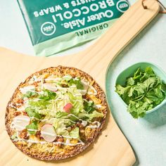 a pizza sitting on top of a wooden cutting board next to a bowl of salad