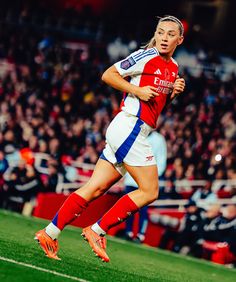 a female soccer player in action on the field with fans watching from the bleachers